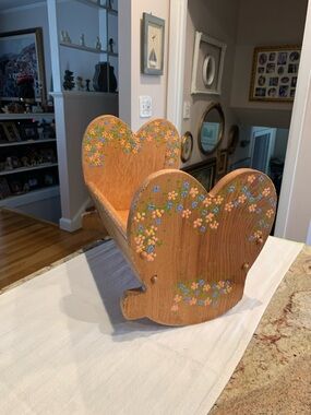 Vintage wooden doll cradle heart-shaped design painted with floral details.